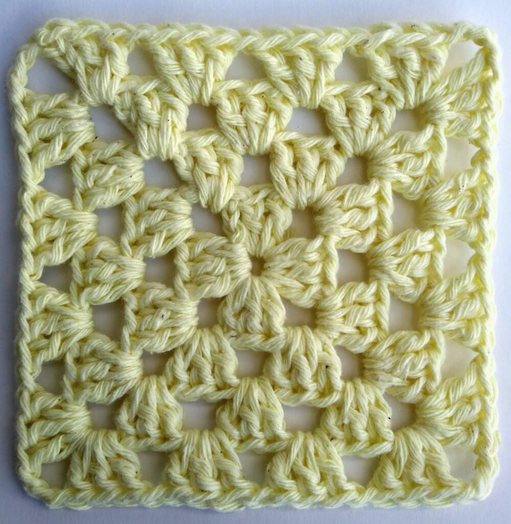 Primer plano del cuadrado al crochet clásico tejido con grupos de 3 varetas y ángulos calados