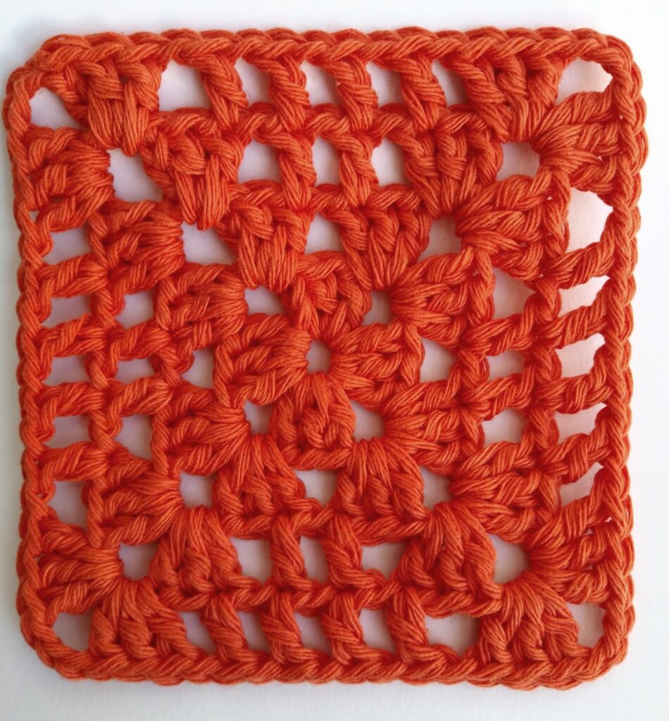 Cuadrado al crochet para principiantes modelo calado en primer plano Primer plano de cuadrado al crochet para principiantes con diseño calado y ángulos definidos tejido en un solo color