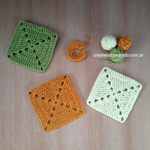 Comparación de cuadrados al crochet modelo compacto Tres cuadrados al crochet del modelo compacto tejidos en colores variados colocados sobre superficie plana