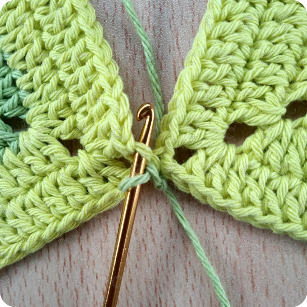 Aguja de crochet uniendo cuadrados al crochet de arriba hacia abajo manteniendo la unión plana